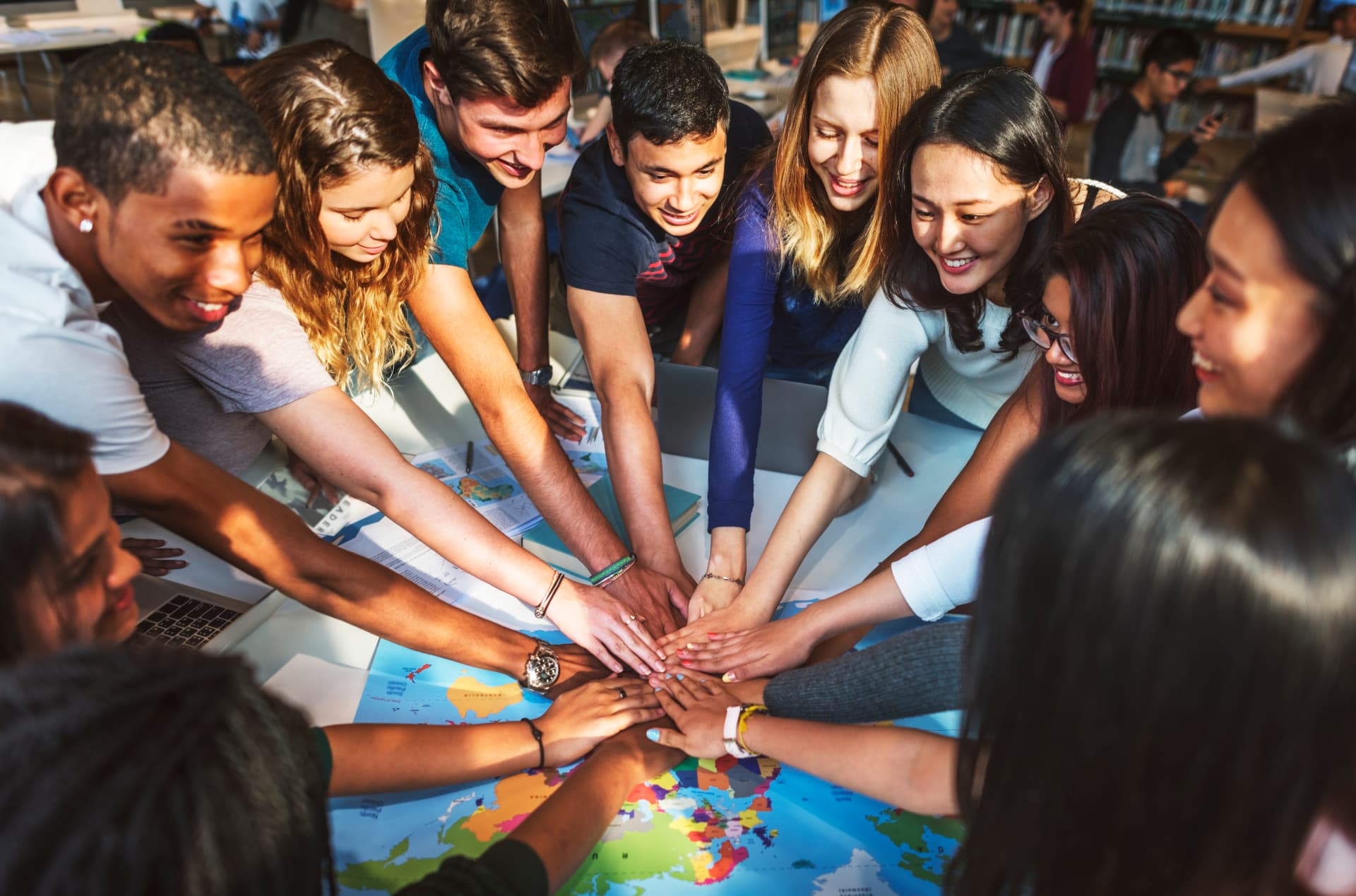 Team van Derek Prince Ministries met handen op elkaar rond een wereldkaart